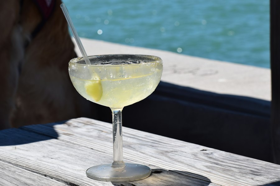 Un cóctel con limón en una mesa de madera frente al mar azul